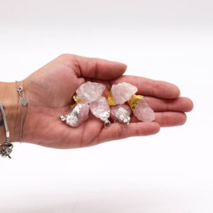 Seis colgantes de cuarzo rosa en bruto con casquillo de baño dorado y plateado sobre fondo blanco