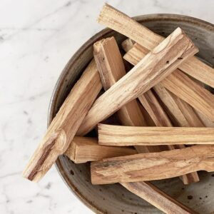 Palitos de palo santo en un cuenco de cerámica sobre mármol blanco