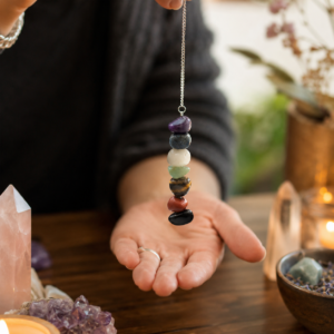 Péndulo de los chakras con siete piedras rodadas de colores, de la violeta a la negra, colgado de una cadena plateada
