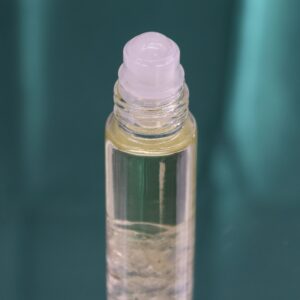 Frasco roll-on de vidrio con aceite perfumado, aplicador de bola y trocitos de cristal de roca en el fondo