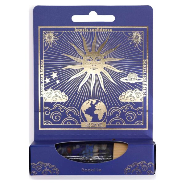 Envase azul de perfume roll-on con El Sol del tarot en dorado y el frasco de sodalita en la ventana