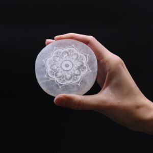 Placa redonda de selenita blanca con un mandala floral grabado en el centro
