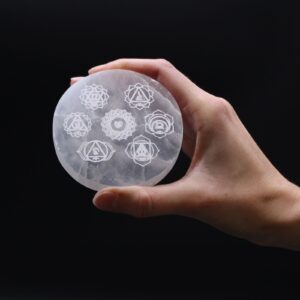 Placa redonda de selenita con los siete símbolos de los chakras grabados en blanco