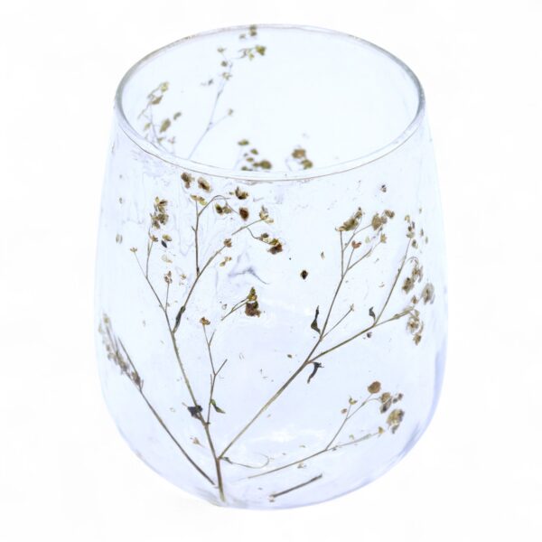Portavelas de vidrio transparente con forma de jarrón y ramitas de florecillas secas dentro de la pared