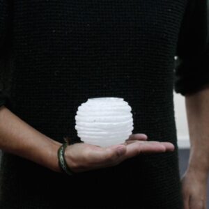 Portavelas de selenita blanca en forma de bola con surcos horizontales tallados