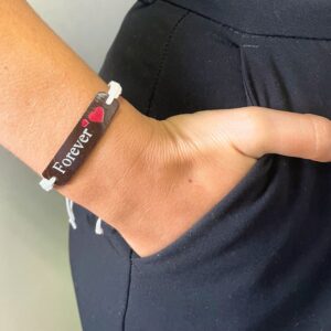 Pulsera de la amistad de cordón blanco trenzado con placa de coco y la palabra Forever, en la muñeca; se envía una, con palabra y color al azar