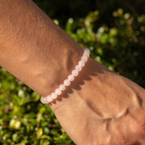 Pulsera elástica fina de cuentas de cuarzo rosa de 6 mm colgando de su tarjeta ilustrada