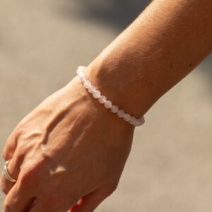 Pulsera elástica fina de cuentas de cuarzo rosa de 6 mm colgando de su tarjeta ilustrada