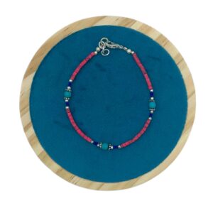 Pulsera de tubitos rosa coral con vetas oscuras y tres cuentas redondas color turquesa entre rondeles plateados, sobre fondo blanco