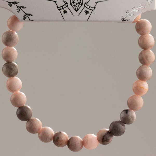 Pulsera elástica fina de cuentas de jaspe rosa con motas grises, vista de cerca