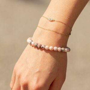 Pulsera elástica fina de cuentas de jaspe rosa con motas grises, vista de cerca