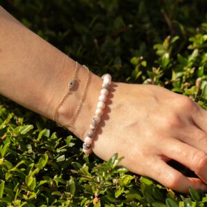 Pulsera elástica fina de cuentas de jaspe rosa con motas grises, vista de cerca