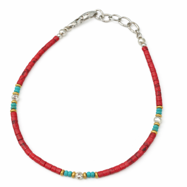 Pulsera fina de tubitos rojo coral con grupos de cuentas turquesa, bolitas doradas y una perlita blanca en el centro, sobre fondo blanco