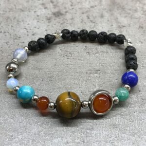 Pulsera de lava negra con ocho cuentas de colores como planetas y detalles de metal plateado