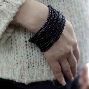 Cuatro pulseras multivuelta de cuentas de madera de coco en negro, beige, verde y rojo, con cierre de madera oscura