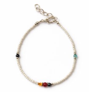 Pulsera de perlitas blancas de imitación con cuentas facetadas negra, verde agua, ámbar, roja y gris, mosquetón y cadenita, sobre fondo blanco