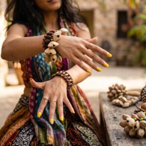 Pulsera sonajero con quince cáscaras de kenari alrededor de cuentas de madera y cuentas verdes, amarillas y rojas