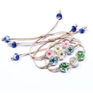 Cuatro pulseras de cordón beige con tres cúpulas de vidrio con flores secas de colores cada una