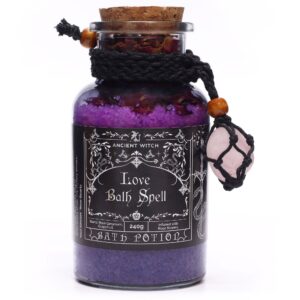 Amuleto de cuarzo rosa en red de cordón negro con cuenta de madera, junto a un frasco de sales de baño violetas