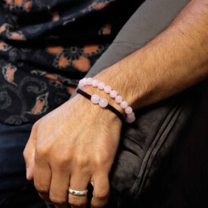 Pulsera elástica de cuentas de cuarzo rosa y pulsera de cordón rojo trenzado con dos cuentas de cuarzo rosa, sobre su tarjeta