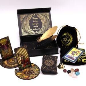 Set de tarot dorado abierto con las cartas en soportes redondos, la caja negra, una pluma dorada, bolsa, tapete, campanilla, piedras y la guía