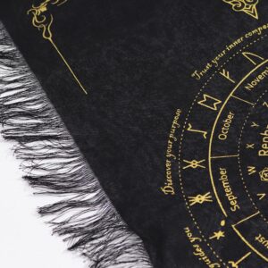 Detalle de tela de algodón negro con flecos y una rueda de runas y meses estampada en tono dorado