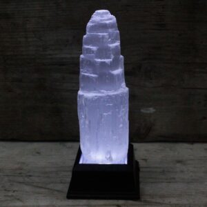 Torre de selenita blanca natural de 15 cm tallada en escalones, sobre madera con hojas de hiedra