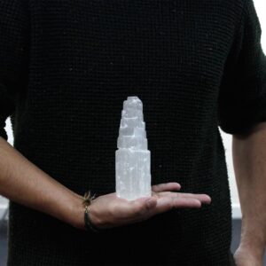 Torre de selenita blanca natural de 15 cm tallada en escalones, sobre madera con hojas de hiedra