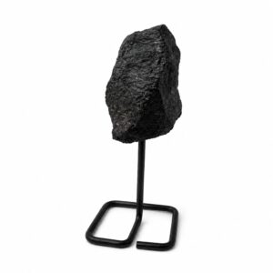Turmalina negra en bruto de superficie rugosa sobre un soporte de varilla de metal negro con base cuadrada