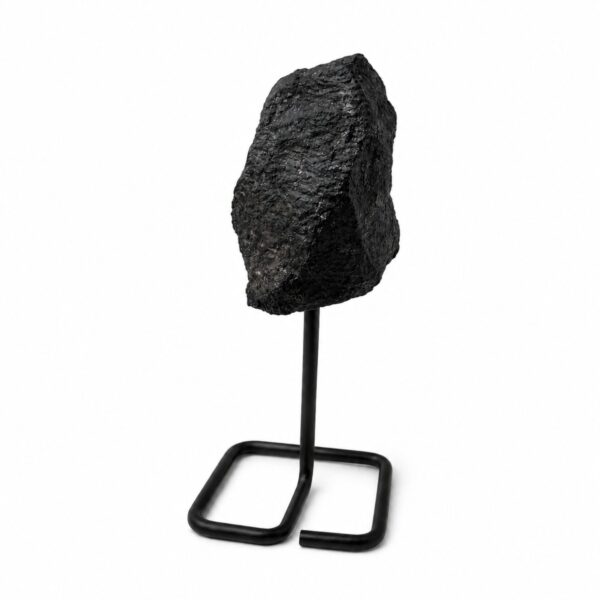 Turmalina negra en bruto de superficie rugosa sobre un soporte de varilla de metal negro con base cuadrada