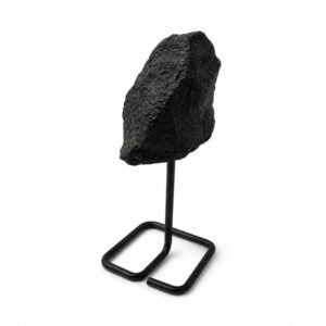 Turmalina negra en bruto de superficie rugosa sobre un soporte de varilla de metal negro con base cuadrada