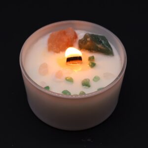 Vela del chakra del corazón en vaso blanco con cuarzo rosa y jade verde sobre la cera, apoyada en su caja verde
