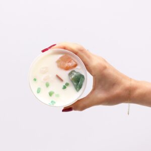 Vela del chakra del corazón en vaso blanco con cuarzo rosa y jade verde sobre la cera, apoyada en su caja verde