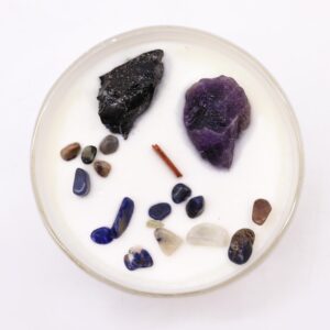 Vela del chakra del plexo solar en vaso blanco con amatista, ágata negra y lascas de colores, sobre su caja amarilla
