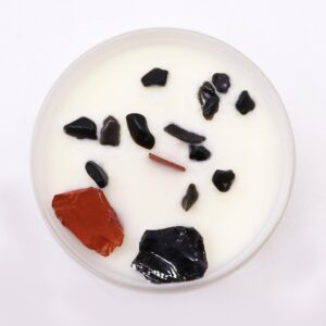 Vela del chakra raíz en vaso blanco con jaspe rojo y ágata negra sobre la cera, apoyada en su caja roja ilustrada