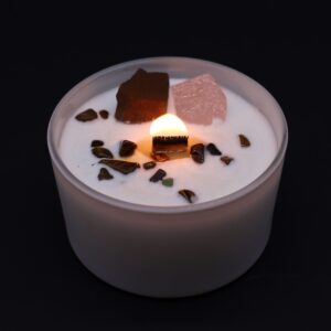 Vela del chakra sacro en vaso blanco con cuarzo rosa y ojo de tigre sobre la cera, apoyada en su caja naranja