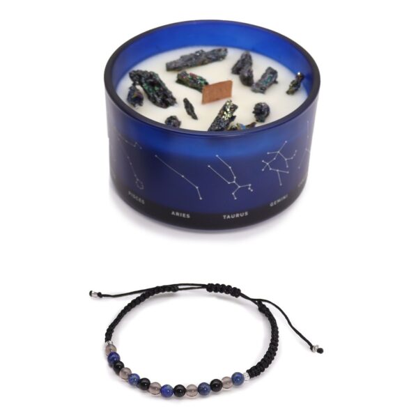 Vela de soja en vaso azul con constelaciones y trozos de pirita, junto a una pulsera de cordón negro con cuentas de obsidiana, cuarzo ahumado y lapislázuli