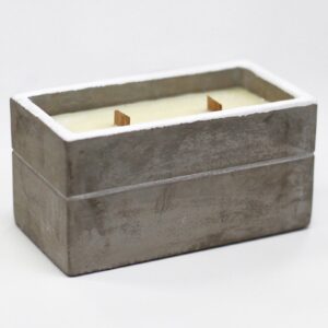 Vela rectangular en caja de hormigón gris con dos mechas de madera encendidas