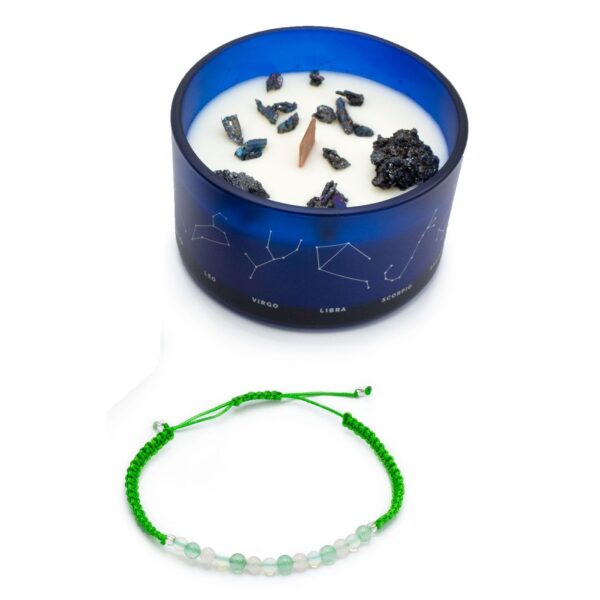 Vela de soja en vaso azul con constelaciones y trozos de pirita, junto a una pulsera de cordón verde con cuentas de aventurina, cuarzo rosa y cuentas blancas
