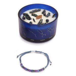 Vela de soja en vaso azul con constelaciones y trozos de pirita, junto a una pulsera de cordón gris azulado con cuentas violeta, azules y gris metálico