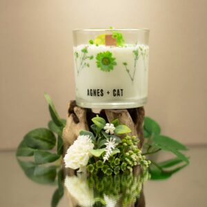 Vela de soja en vaso de vidrio con flores secas verdes junto a su caja blanca