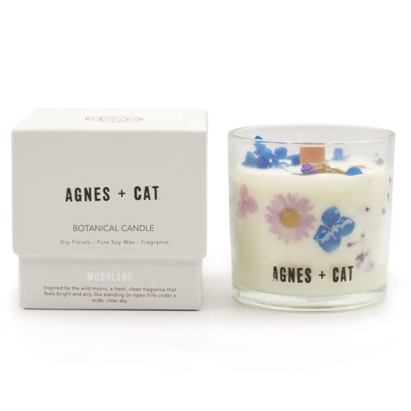 Vela de soja en vaso de vidrio con flores secas azules y lilas junto a su caja blanca