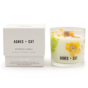 Vela de soja en vaso de vidrio con flores secas amarillas y helecho junto a su caja blanca