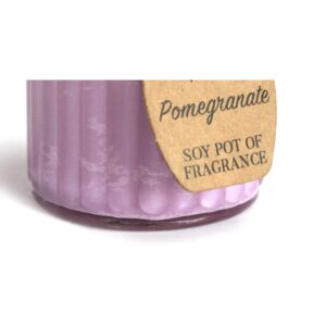 Vela de soja de color malva en tarro de cristal estriado con etiqueta kraft que dice Pomegranate