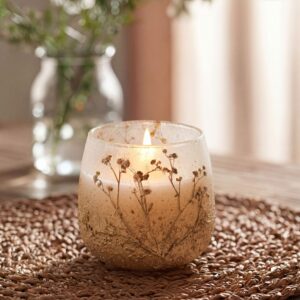 Vela en tarro de vidrio esmerilado blanco y arena con ramitas de flores silvestres secas incrustadas