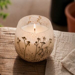 Vela en tarro de vidrio esmerilado blanco y arena con ramitas de flores silvestres secas incrustadas