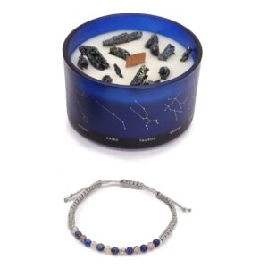 Vela de soja en vaso azul con constelaciones y trozos de pirita, junto a una pulsera de cordón gris con cuentas azules de lapislázuli y blancas de ágata musgo