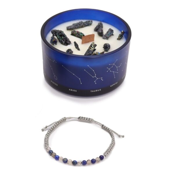 Vela de soja en vaso azul con constelaciones y trozos de pirita, junto a una pulsera de cordón gris con cuentas azules de lapislázuli y blancas de ágata musgo