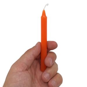 Caja naranja de velas del chakra sacro con una vela naranja fina de pie a su lado
